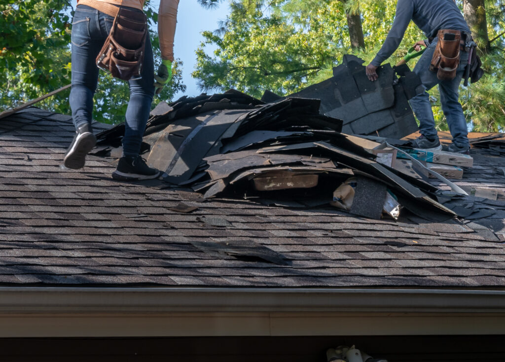 Men on roof removing damaged shingles